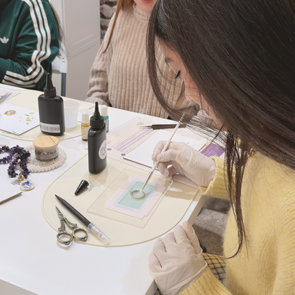 Resin and natural flower jewellery workshop in Barcelona: participants making their own necklace with gloves and tweezers