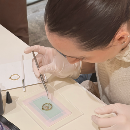 Participant placing a dried flower with tweezers in a resin pendant during a botanical jewellery workshop in El Born
